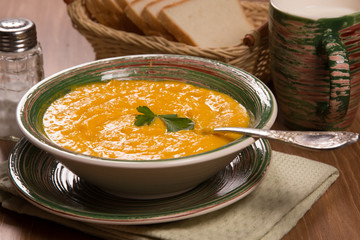 Pumpkin cream soup in a green ceramic plate on the kitchen table
