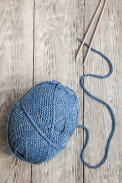 blue ball of yarn with spokes on grey wooden background