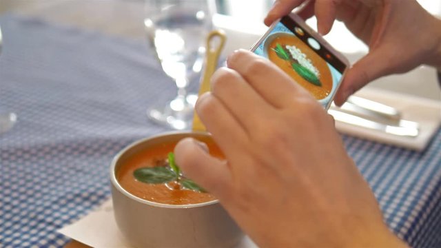 Woman taking photos of tomato soup by smartphone in 4k slow motion 60fps