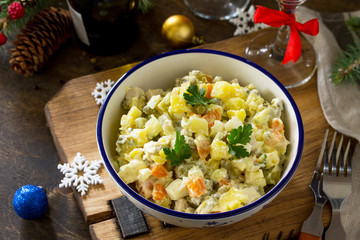 Winter holiday salad. Russian traditional salad Olivier with vegetables and chicken on wooden table. Traditional Russian cuisine.