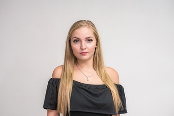 Studio portrait of a beautiful blonde girl in a dress on a white background in different poses with different emotions