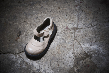 Abandoned baby shoe lying on old concrete floor. Lost children's shoes.