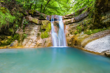 Fototapeta na wymiar Beautiful waterfall in mountain of Caucasus. Summer landscape with waterfall and water stream in forest of Caucasus mountain.