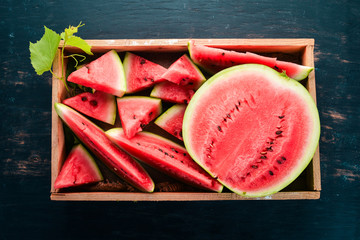 Watermelon in a wooden box. Sliced to pieces of watermelon. On a wooden background. Free space for text. Top view.