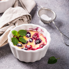 Berry clafouti. Traditional french sweet fruit dessert clafoutis with raspberries and blueberries on gray concrete background. Healthy gluten free food concept with copy space.