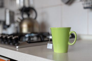 A mug with tea on the kitchen table. Preparing homemade hot drinks.