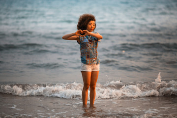 Young mixed race woman on a tropical beach in the light of the amazing sunset.