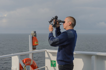 Seaman with sextant on navigational bridge