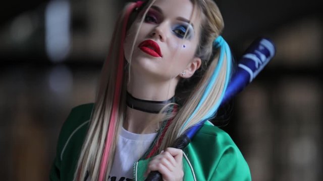 Unusual woman with fantastic makeup and unconventional hairstyle holding baseball-bat