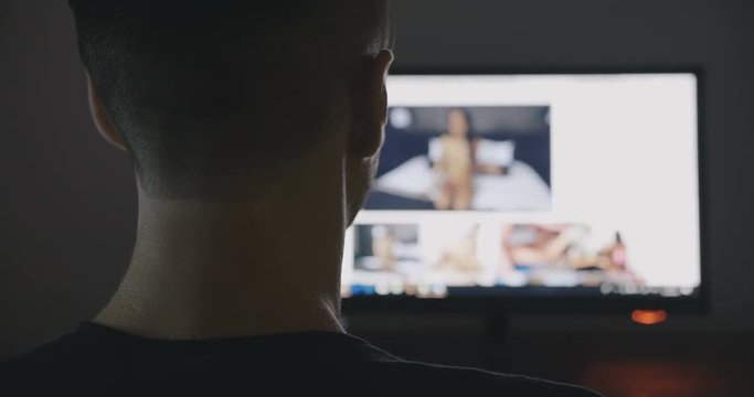 Back view of man communicates through porn chat virtual sex at night