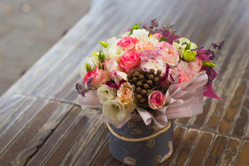 bouquet of multicolored roses decorated in a box on a wooden background