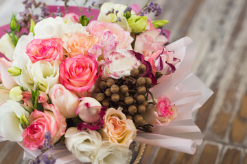 bouquet of multicolored roses decorated in a box on a wooden background
