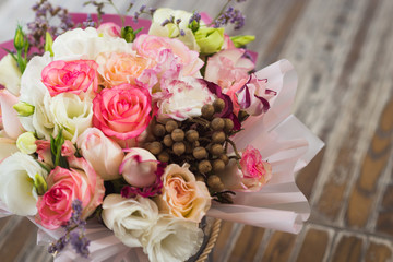 bouquet of multicolored roses decorated in a box on a wooden background