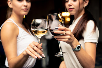 glasses with red and white guilty in the hands of beautiful girls dressed in white blouses