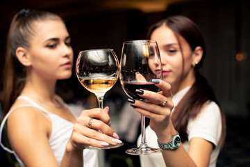 glasses with red and white guilty in the hands of beautiful girls dressed in white blouses