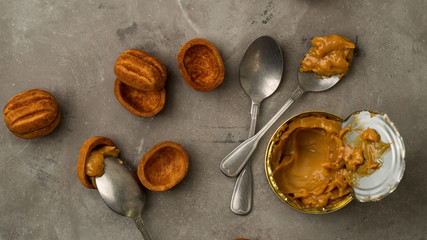 Vintage silver spoons with caramelized milk and brown cookies of walnuts shape on grey concrete background