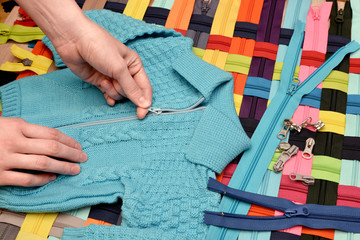 Fastening on a zipper a knitted sweater. © kobzev3179