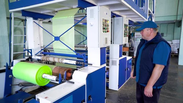 Worker checking and set up LDPE Plastic Blown film bag making machine inside cleanroom for industrial export.