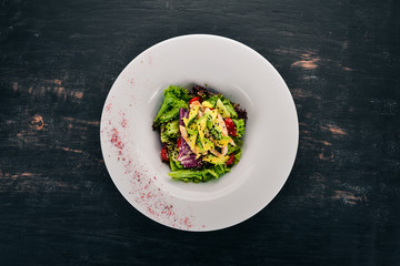 Vegetable salad with chicken fillet and avocado. On a wooden background. Free space for text. Top view.