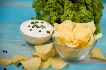 Potato chips in bowl on a blue wooden background