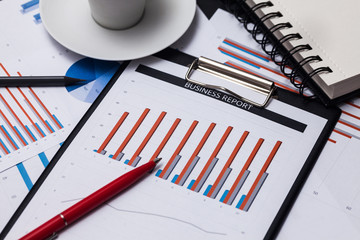 Business reports and cup of coffee. Blue graphs and charts and documents on black background. High...