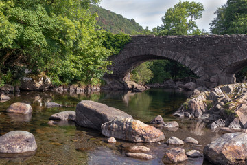 Fototapeta na wymiar Old stone bridge over River Duddon in Ulpha in the Lake District National Park, UK. Scenic view of English countryside on a sunny day