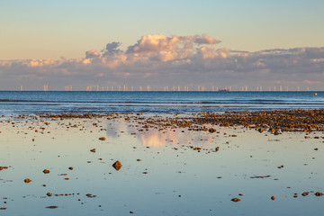 Low tide at Worthing beach, with evening light and a view of a wind farm on the horizon