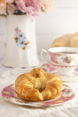A Freshly Baked Buttery Croissant Laid on the Table for Breakfast with Hot Black Coffee
