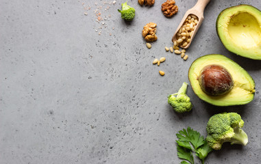 Variety of fresh green vegetables and nuts on grey concrete background for the healthy and...