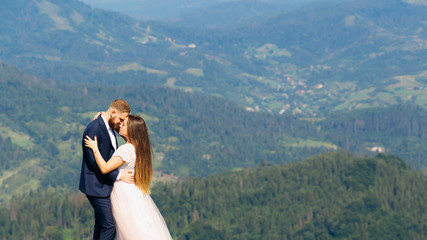sensual hugs newlyweds against the backdrop of fantastic mountains with green forests