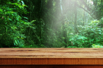Wooden table and blurred green forest background.