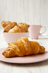 Fresh croissants with cup of coffee, side view. Selective focus.