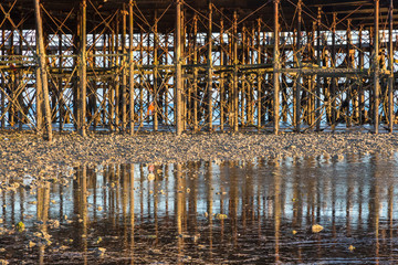 A pier at low tide with the reflections in the shallow water