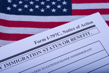 Form I - 797C Application to extend change nonimmigrant status (Notice of action, I539, immigration status) on flag of USA background. Diagonal view.