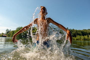 Boy emerging from under water with big splash in wood lake