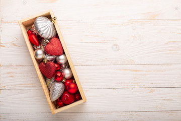 Box with silver and red christmas gifts on white wooden background. Top view. Copy space