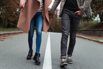 Easy autumn walk. Part of young beautiful couple walking in the park in autumn