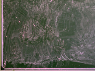 stamps of children's palms smeared with pink chalk on a green school chalkboard