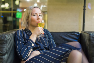 Young girl on a leather chair drinking white wine