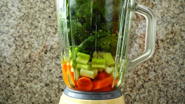Cocktail from carrots, a stalk of a apium and spinacia. Slow motion.	Process of preparation of cocktail.