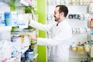 Smiling man pharmacist browsing assortment