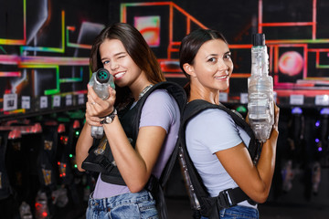 Girl took aim and holding guns during laser tag game in dark labyrinth indoor