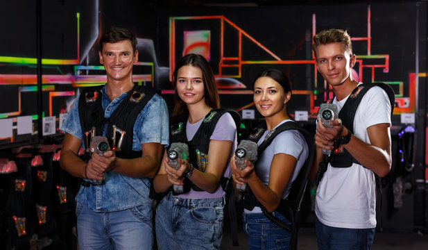 Smiling young people with laser guns having fun together in labyrinth