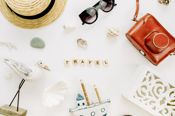 Word Travel, bird figurine, toy boat, retro camera, seashells and straw hat on white background. Flat lay, top view travel blog hero header.