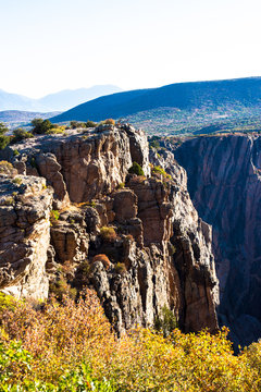 Steep, sheer cliffs and colorful fall foliage in early morning light characterize Black Canyon of the Gunnison National Park in Colorado