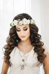 Gorgeous Beautiful Bride portrait with wedding makeup and long curly hair wears cristal wreath and bridal lace dress.