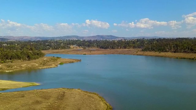 Drone footage moving left to right 30 meters above water level showing Lake Dyer, with a flock of white birds flying out of the frame.