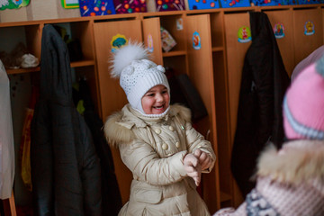 girl wears gloves before going out of kindergarten preschool. baby put on winter. Winter clothes...