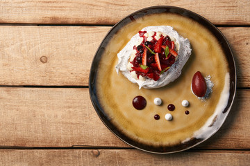 Pavlova fruit cake and berry ice cream dessert on wooden table background, close-up