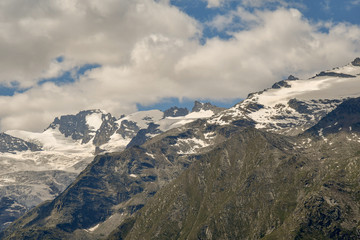 Cime di montagna con ghiacciai perenni e cielo azzurro con nubi in Valle d'Aosta, Alpi Italiane